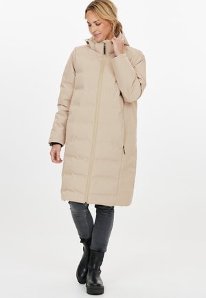 Beige pufferjas, tot op de knie, met een hoge kraag, een volledige ritssluiting en twee zijzakken. Vloeiende textuur met een matte afwerking.