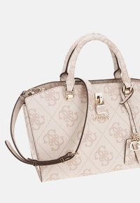 Sac à main en cuir crème matelassé avec un motif logo subtil, des accents en matériel doré, des poignées doubles et une bandoulière amovible.