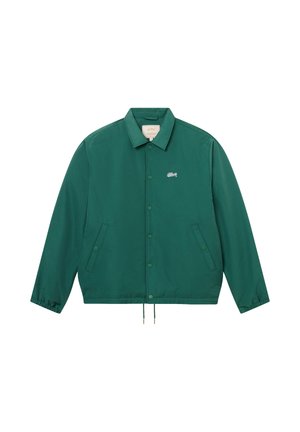 Veste boutonnée verte avec col, poignets élastiques, deux poches latérales et petit logo blanc sur le côté gauche de la poitrine.