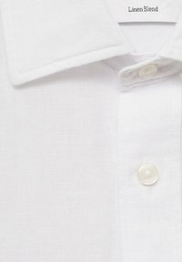 White linen blend shirt with a buttoned collar and a single button closure. Smooth texture with a subtle weave pattern.