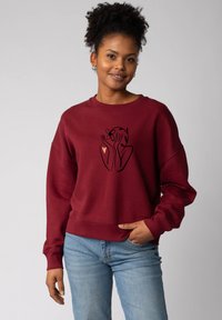 Sweat-shirt bordeaux au design court, avec un dessin en ligne noire de mains et d'une fleur. Texture douce, coupe oversize et poignets côtelés.