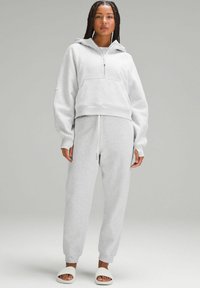 Grå zip-up, kort hoodie med framficka, matchad med byxor i joggerstil. Sweatshirten har vida ärmar; byxorna har elastiska muddar.