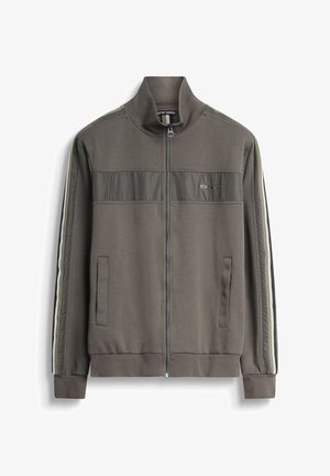 Veste de survêtement zippée, couleur olive, avec deux poches latérales, en tissu texturé, et des rayures verticales blanches et noires le long des manches.