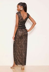 Sort maxi-kjole i blonder med en tætsiddende overdel, V-ryg og korte ærmer. Kjolen har en gennemsigtig, let gennemsigtig struktur og en figursyet silhuet.