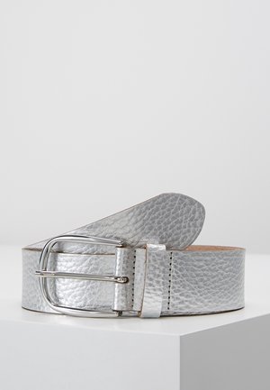 Zilverkleurige, getextureerde leren riem met een glanzende metalen gesp, opgerold liggend op een witte ondergrond tegen een effen achtergrond.