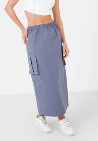 Hellblauer Cargo-Rock mit elastischem Bund, zwei Seitentaschen und geradem Schnitt. Kombiniert mit weißen Sneakers für einen Kontrast.