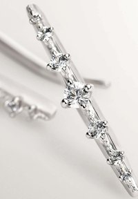 Horquilla de plata con seis piedras preciosas transparentes, cortadas en forma redonda, dispuestas en una línea con acentos metálicos, textura suave y acabado pulido.