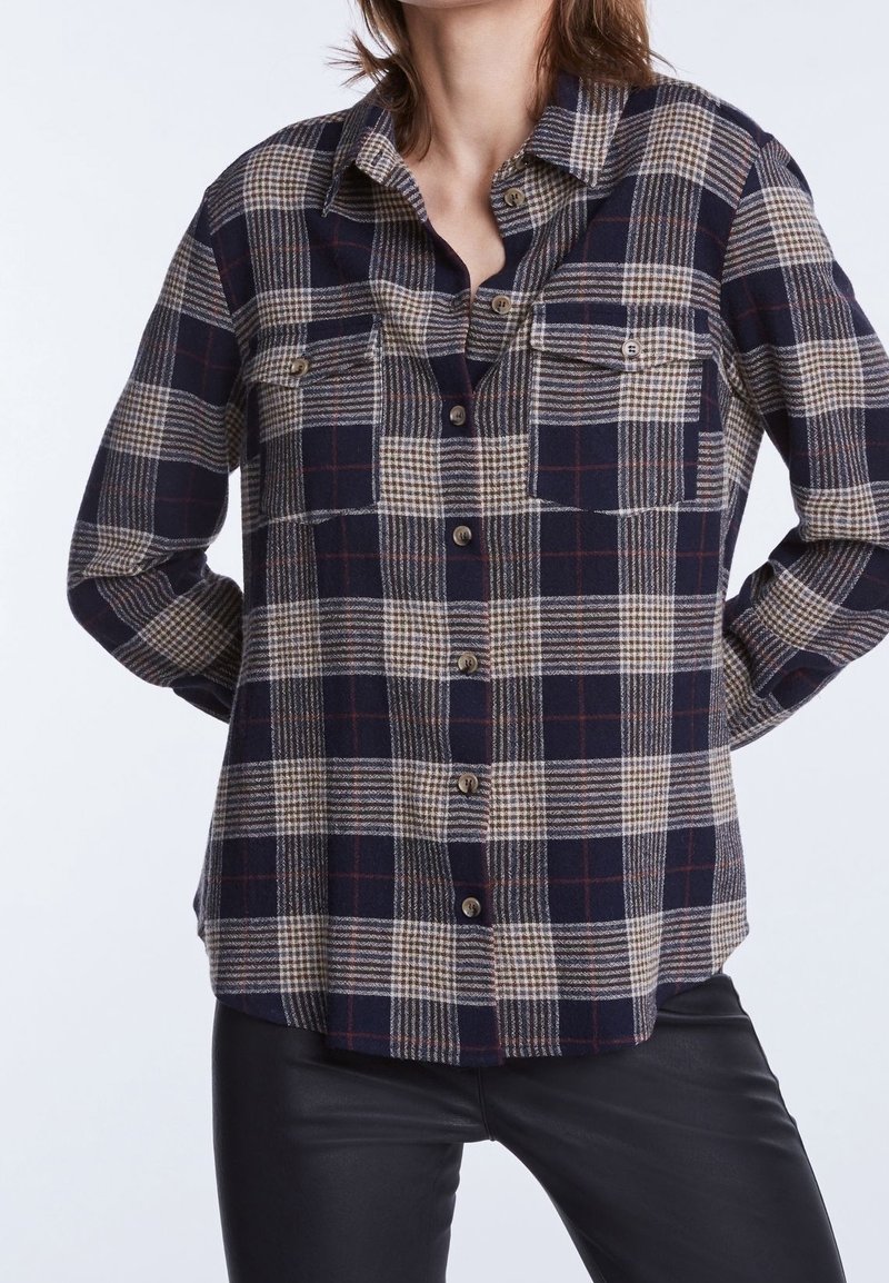 Chemise à carreaux boutonnée en bleu marine, beige et rouge. Dotée de deux poches poitrine, de manches longues et d'une coupe décontractée. Texture douce avec un motif à carreaux.