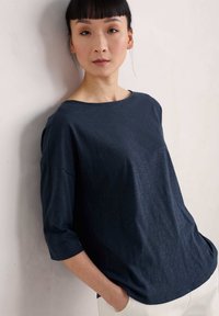 Top ligero de color azul marino, de corte relajado con escote redondo y mangas de tres cuartos. Textura suave, diseño casual y estilo minimalista.