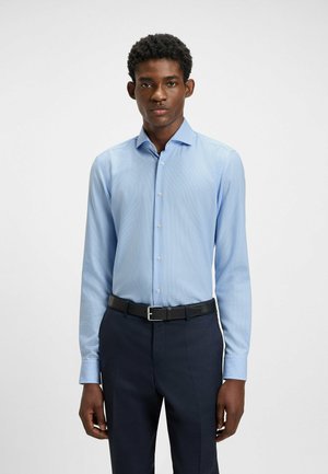 Lichtblauwe, langemouwen shirt met een subtiel ruitpatroon, button-down kraag en een getailleerd design, gecombineerd met donkerblauwe broek en riem.