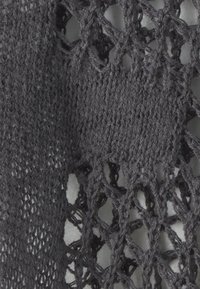 Tejido de punto gris oscuro con un patrón abierto parecido a un encaje. La textura parece suave, con tamaños de puntadas variables que crean un aspecto delicado.