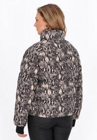 Padded jacket z wysokim kołnierzem, zdobiony czarno-beżowym wzorem węża, z teksturowanej tkaniny i prążkowanymi czarnymi mankietami.