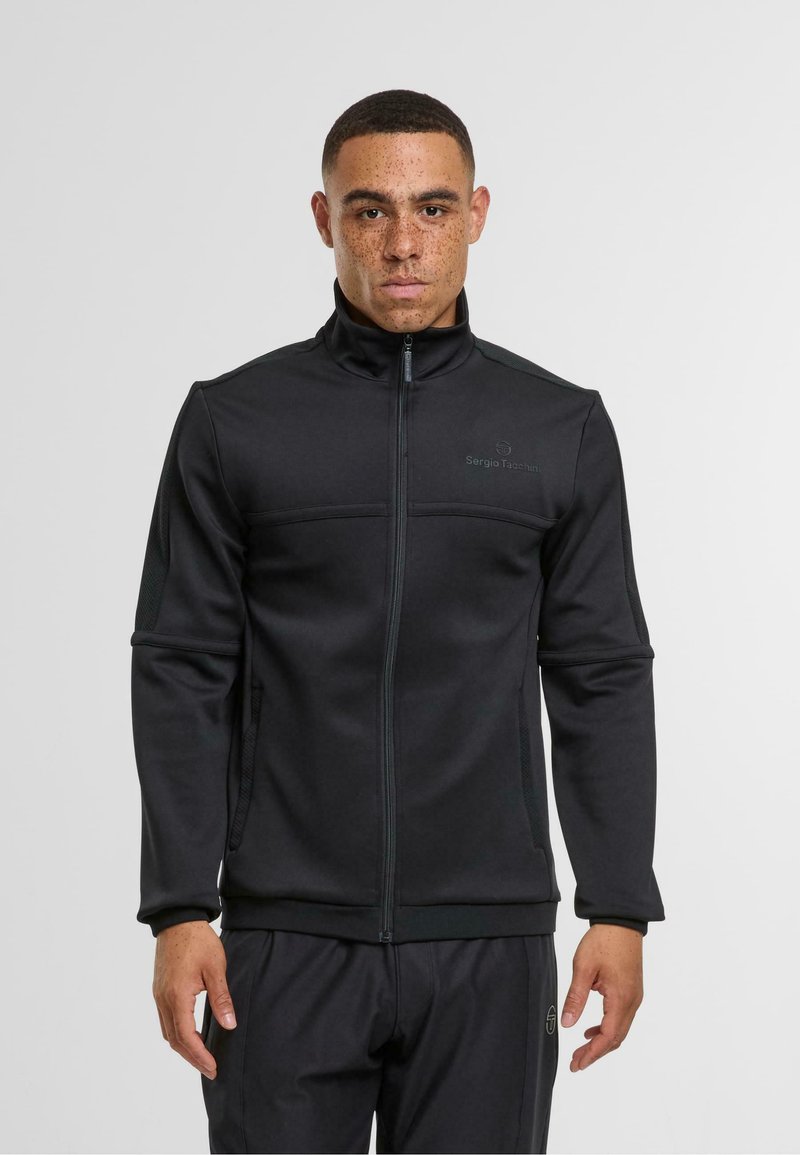 Černá zipová bunda z měkké látky, s vysokým límcem, bočními panely a diskrétním logem na prsou. Hladká textura a přiléhavý střih.