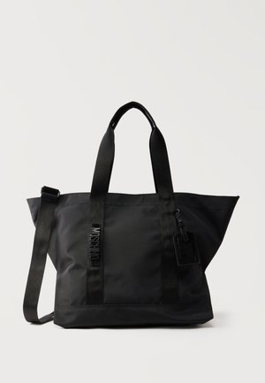 Czarna nylonowa torba na ramię z dwoma górnymi uchwytami, regulowanym paskiem na ramię oraz małą przymocowaną metką, z pionowym napisem MOSCHINO na przodzie.