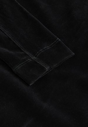 Tejido de terciopelo negro con una textura suave y una manga doblada, que presenta una costura cuidadosa a lo largo de los bordes, creando un acabado limpio.