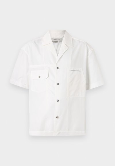 Krótki rękaw, biały shirt wykonany z lekkiego materiału, z kołnierzykiem typu point, zapięciem na guziki, dwiema kieszeniami na piersi oraz kontrastowym przeszyciem.