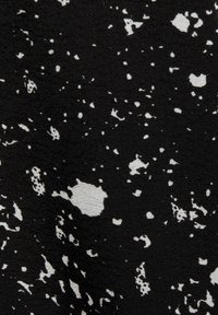 Tela negra con un patrón de salpicaduras en blanco, con manchas y puntos de diferentes tamaños que crean una apariencia texturizada.