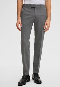 Pantaloni grigi da uomo con un motivo a quadretti sottile, taglio sartoriale, design a vita bassa e vita standard, abbinati a scarpe eleganti nere.