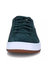 Sneakers in pelle scamosciata verde scuro con suola bianca. Presentano lacci e dettagli con logo sul lato. Forma arrotondata e superficie texturizzata.