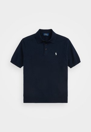 Polo shirt bleu marine en coton. Il présente une patte de boutonnage à trois boutons, des manches courtes et un petit logo brodé sur la poitrine gauche.