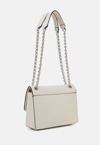 Krémová kožená kabelka se strukturovaným tvarem, stříbrnými řetízkami na rameno a kontrastními černými okraji. Má hladký povrch.