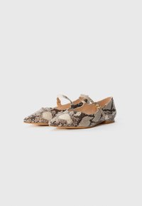 Una coppia di scarpe flat a punta con un motivo in serpente beige e nero e sottili cinturini alla caviglia con piccole fibbie dorate.