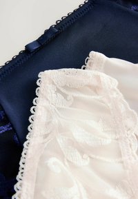 Set de lenjerie care prezintă un top din satin de un albastru închis, cu dantelă, completat de o piesă delicată din dantelă roz deschis, cu un model floral.