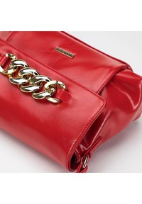 Bolso de mano de cuero rojo con un acento de cadena dorada, que presenta una textura suave, forma rectangular y un cierre de solapa.