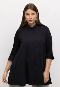 Zwart gekraagde blouse met driekwartmouwen, met een losse pasvorm en een gladde stof, details zijn onder andere een knoopsluiting aan de voorkant.