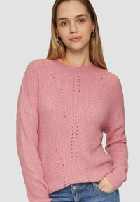 Pull en tricot rose avec un col rond, présentant un motif texturé et de petits détails découpés. Manches longues et coupe décontractée.