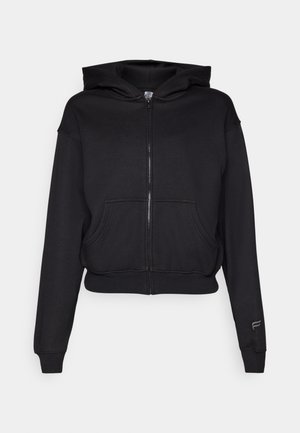 Black cropped hoodie made from soft fabric, featuring a zip closure, front pockets, ribbed cuffs, and a logo accent on the sleeve.