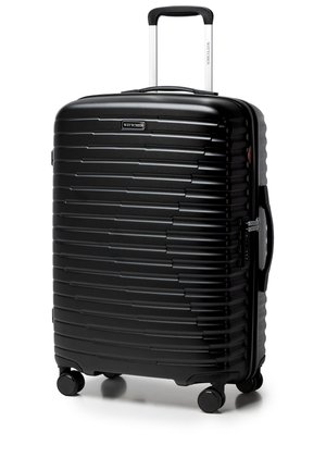 Czarna walizka o twardej skorupie z poziomymi żebrowaniami, cztery obrotowe kółka, wysuwana rączka, boczny uchwyt oraz wbudowany zamek.
