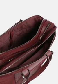 Borsa a tracolla in pelle bordeaux con molteplici scomparti con zip, esterno liscio, doppi manici e un ampio interno foderato in tessuto coordinato.