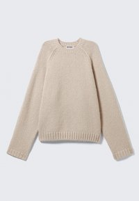 Beige gebreide trui met lange raglanmouwen en geribbelde manchetten en zoom, plat gelegd op een lichte achtergrond.