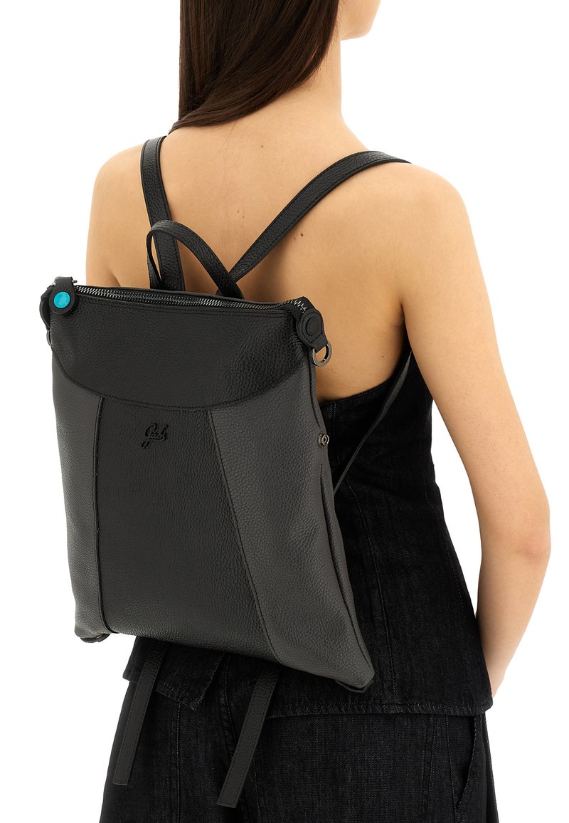 Zaino in pelle nera con finitura testurizzata, chiusura con zip e spallacci regolabili. Presenta un bottone accentato blu vicino alla parte superiore.