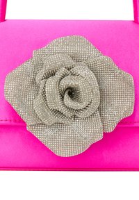 Rosa håndtaske med en tekstureret overflade. Har en sølvfarvet rhinestone blomst i midten, der tilføjer dimension og detaljer til designet.