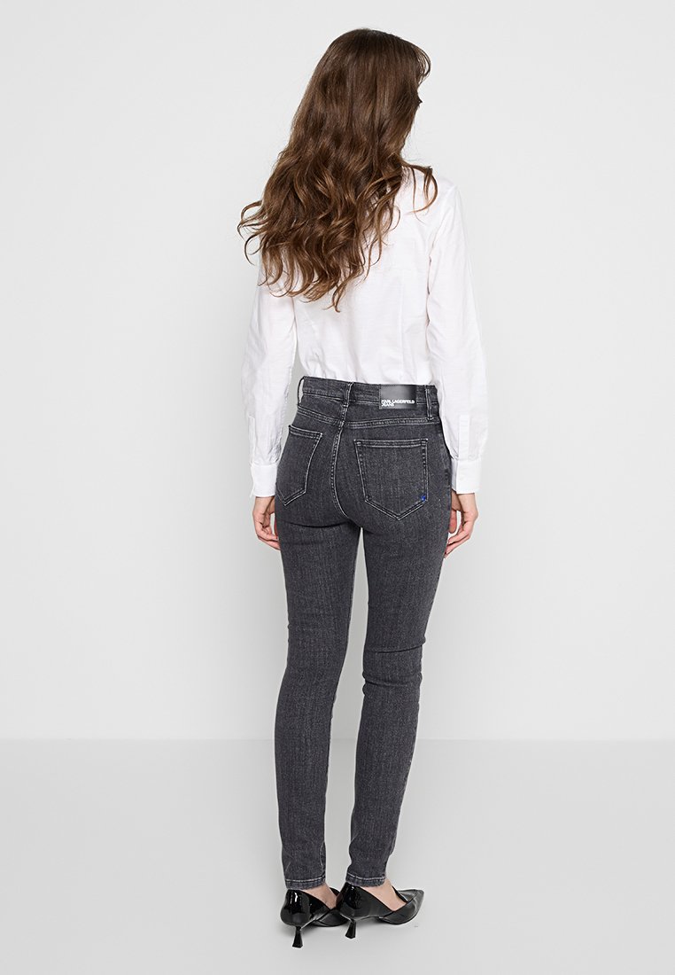 Jean skinny gris foncé à taille haute, avec des coutures contrastées et deux poches arrière. Fabriqué en denim avec une texture lisse.