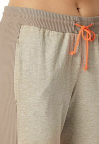 Helle beige Sportshorts mit gerippten Seitenteilen, einem elastischen Bund und einer orangen Kordel. Weicher Stoff mit lockerer Passform.