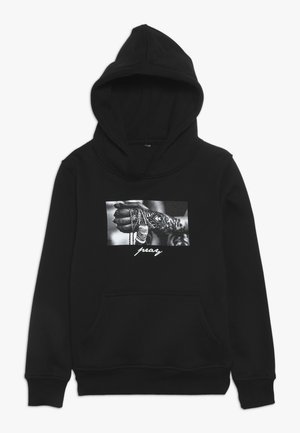 Sweat à capuche noir en coton avec une poche sur le devant, arborant une impression graphique en noir et blanc d'une main tenant des chaînes et le mot « prier ».