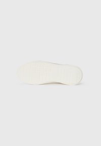 Talpa de pantof alb din cauciuc, cu o suprafață texturată ce prezintă modele în grilă și linii ridicate pentru aderență. Design ușor și flexibil.