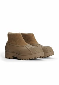 Ruske rubber ankle boots med en blød suede-overdel, struktureret sål og forstærket tå, med en afrundet form og side syninger.
