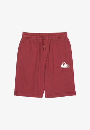 Maroonfarbenes Baumwoll-T-Shirt mit kurzen Ärmeln und Logodetail, kombiniert mit passenden Shorts. Getragen mit weißen Socken und schwarz-türkisfarbenen Sneakern.