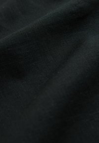 Tissu en lin noir avec une texture lisse, présentant des variations subtiles de teinte et un léger éclat, transmettant une couleur riche et profonde.