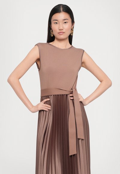 Brown sleeveless dress with a fitted top and pleated, flowing skirt. Features a tied waist and smooth fabric texture that transitions shades.