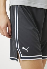 Mustad sportlikud lühikesed püksid valgete küljerebaste ja väikese valge Puma logo kaeluses. Kerge materjal, millel on veidi tekstureeritud viimistlus.