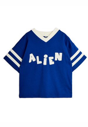 Chemise bleue à manches courtes avec un bord en V blanc, deux bandes blanches sur chaque manche et des lettres blanches formant le mot "ALIEN" sur la poitrine.