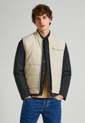 Gilet imbottito con parte frontale beige e maniche blu scuro. Presenta una chiusura con zip, un colletto a coste e una tasca sul petto con bottone a pressione.