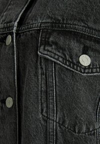 Zwarte denim jacket met een knoopflapzak, stevige stiksels en een gestructureerde afwerking met een subtiele glans.