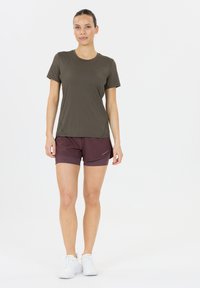 Olivenvihreä lyhythihainen urheilupaita yhdistettynä viininpunaisiin juoksushortseihin, jotka ovat valmistettu kevyistä ja hengittävistä kankaista.