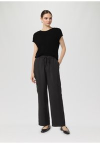 Black short-sleeve top paired with dark gray wide-leg cargo pants featuring side pockets and an elastic waistband. Worn with black flats.